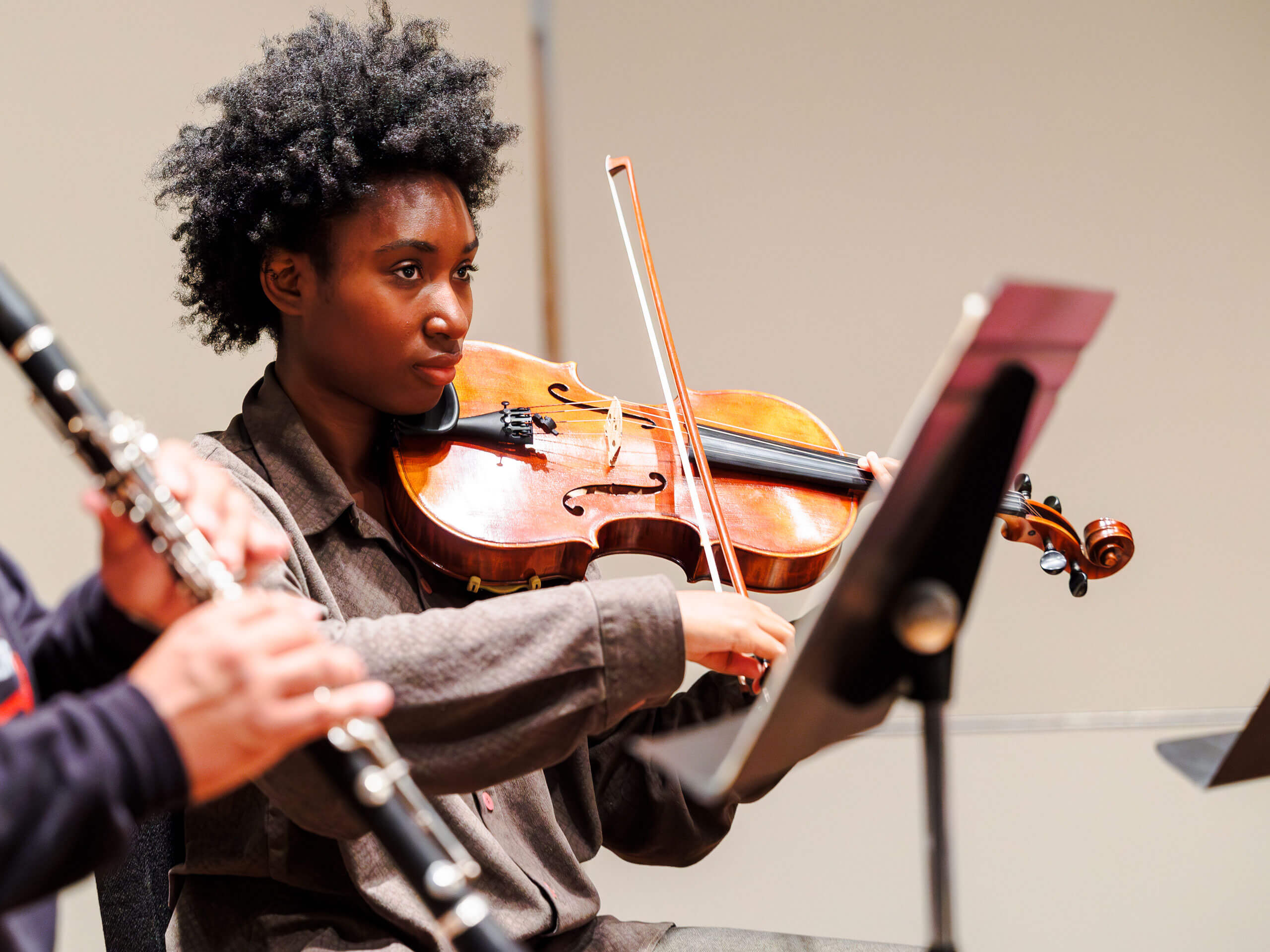 A student plays the violin in a class rehearsal.